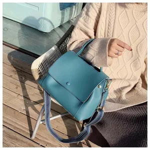 Teal crossbody bag featuring a wide bohemian woven strap and circular metal buckle