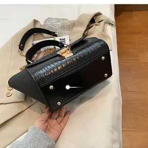Detail showing the bottom of the black crocodile textured handbag with gold protective studs