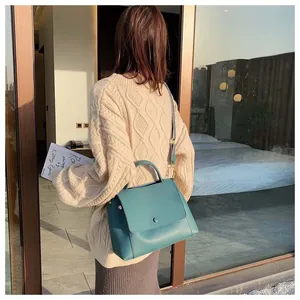 Detail of teal leather handbag featuring a textured woven strap and matte finish