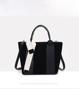 Detail view of black tote bag with matte texture, dual handles and woven decorative ribbon