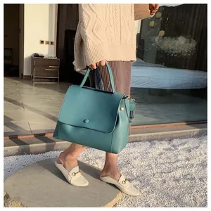 Teal faux leather handbag with round magnetic clasp and wide patterned shoulder strap