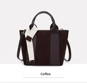 Detail of coffee brown suede tote bag with contrast woven strap and leather handles