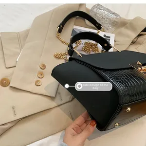 Detail of black wing bag featuring matte fabric, crocodile texture, and gold hardware