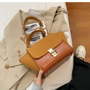 Detail of frosted ginger handbag with crocodile texture and golden swivel lock