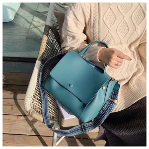 Detail of teal leather handbag featuring a stylish geometric woven wide shoulder strap
