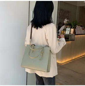 Detail view of light green crocodile texture tote bag with leather tag and woven strap