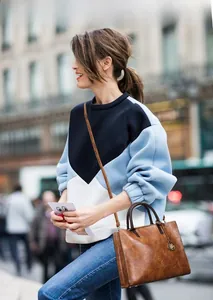 Vue street style d'un sac seau marron avec breloques et un sweatshirt bicolore casual