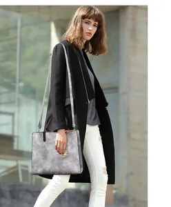 Gros plan sur le sac seau gris avec texture en simili cuir et breloque en métal doré