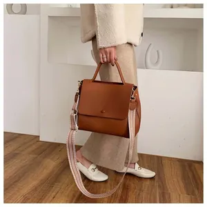 Close-up of brown textured leather handbag with decorative geometric patterned wide strap