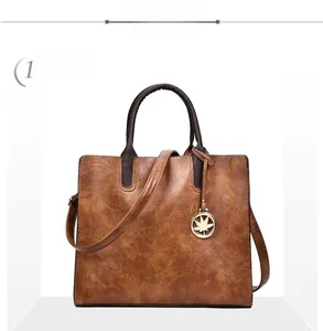 Vue de face d'un sac cabas vintage marron avec texture en cuir ciré et breloque érable
