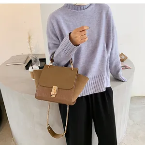 Detailed view of crocodile pattern leather bag with metal handle and chain strap