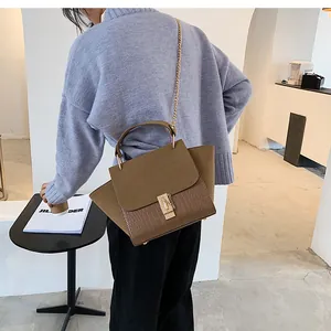 Detail of the chain strap and crocodile texture on the brown wing-shaped handbag
