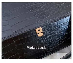 Detailansicht der Kroko-Lederstruktur und des goldenen Metallverschlusses der Handtasche