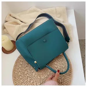 Detail of teal faux leather handbag with striped strap and refined texture close-up