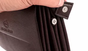 Detail van donkerbruine herenclutch van lycheeleer met magnetische gespsluiting aan de zijkant