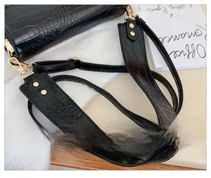 Detail der schwarzen Tasche mit Steinmuster, weichem Gurt und goldenen Nieten