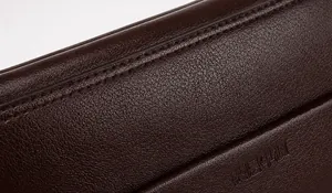 Detailopname van donkerbruin leer met lychee-nerf en duurzame zesdraads stikselafwerking