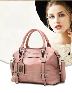 Close-up of pink Boston handbag with metal buckles and detachable leather shoulder strap