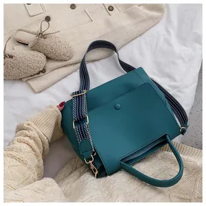 Close-up of teal tote bag with a trendy blue and white striped woven shoulder strap