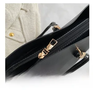 Detail showing smooth gold metal zipper closure on luxury black leather tote bag