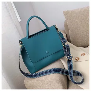 Detail of dark green matte leather bag with patterned wide strap and gold hardware