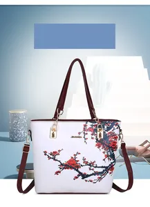 Dettaglio della borsa bianca con graffiti floreali e manici rossi con catena dorata