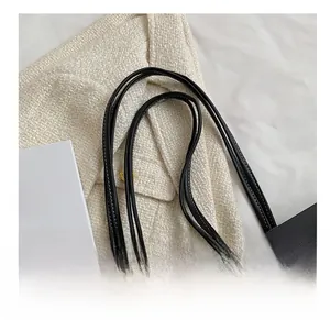 Detail view of black leather tote bag showing slim shoulder strap and gold hardware