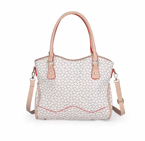Detalle del bolso tote crema con estampado de peces y bordes rojos distintivos en las asas