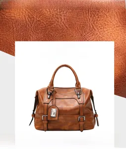 Close-up of litchi-grain faux leather texture on brown Boston handbag with metal tag