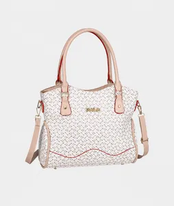 Vista detallada del bolso crema con motivos, bordes rojos y logo dorado en un ángulo de 45 grados
