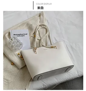 Detail view of cream tote bag with gold hardware accents on white fabric background