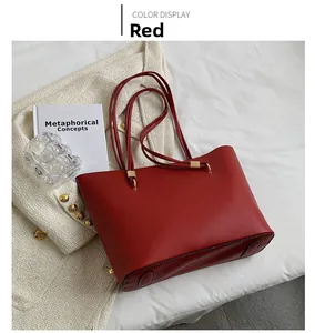 Detail view of red leather tote bag with lychee texture and golden metal hardware