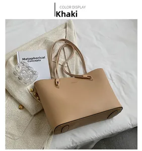 Detail view of khaki leather tote bag with fine shoulder straps on white fabric