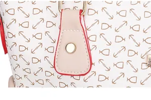 Detalle del bolso blanco con diseño de ancla, borde rojo y herrajes dorados