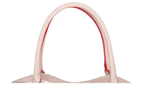 Detalle del asa del bolso blanco con bordes rojos y estampado de patrón dorado