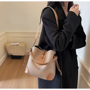 Detail shot of a two-tone bucket bag featuring textured pebble leather and metal ring accents