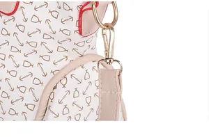 Detalle de bolso blanco con estampado de anclas, bordes rojos y mosquetón de metal dorado