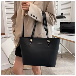 Detail of minimalist black tote bag with gold logo and premium metal hardware accents