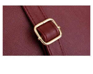 Dettaglio della pelle Saffiano bordeaux e fibbia in metallo dorato sulla borsa a tracolla