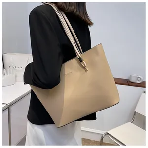 Detail of beige large tote bag showing slim shoulder straps and gold metal hardware