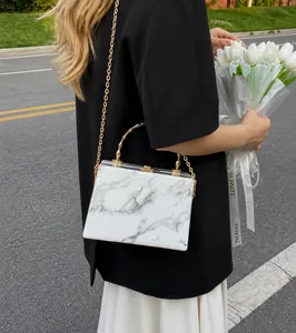 Detail of marble pattern box bag with gold bamboo handle and chain strap on model