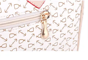 Detalle del tirador de cremallera dorado en bolso bandolera de cuero con estampado