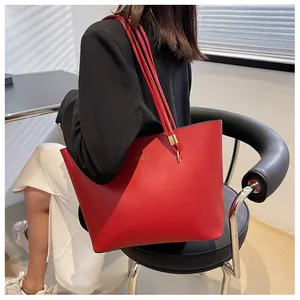 Detail of red synthetic leather tote bag with gold hardware and slim shoulder straps