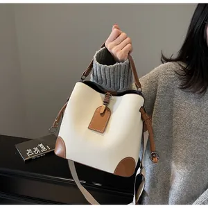 Fashionable cream and brown leather bucket bag held by hand for a chic casual style