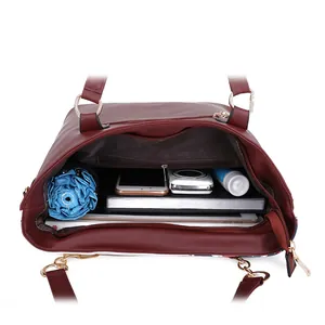 Interno spazioso della borsa tote in ecopelle bordeaux con oggetti quotidiani organizzati