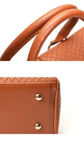 Close-up of brown embossed leather handbag showing gold studs and handle stitching