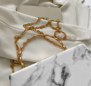 Detail of a marble pattern crossbody bag with golden bamboo handle and metal chain strap