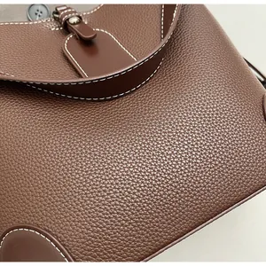 Detailed macro view of dark brown litchi grain leather bucket bag with white stitching