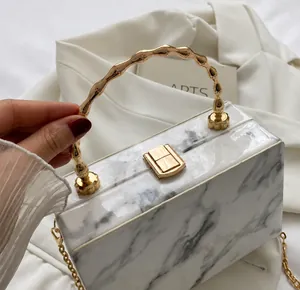Detail of marble pattern crossbody box bag with gold metal bamboo top handle and chain