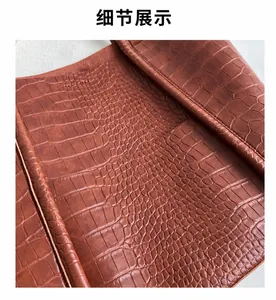 Detailed macro view of brown crocodile texture leather and fine stitching on tote bag